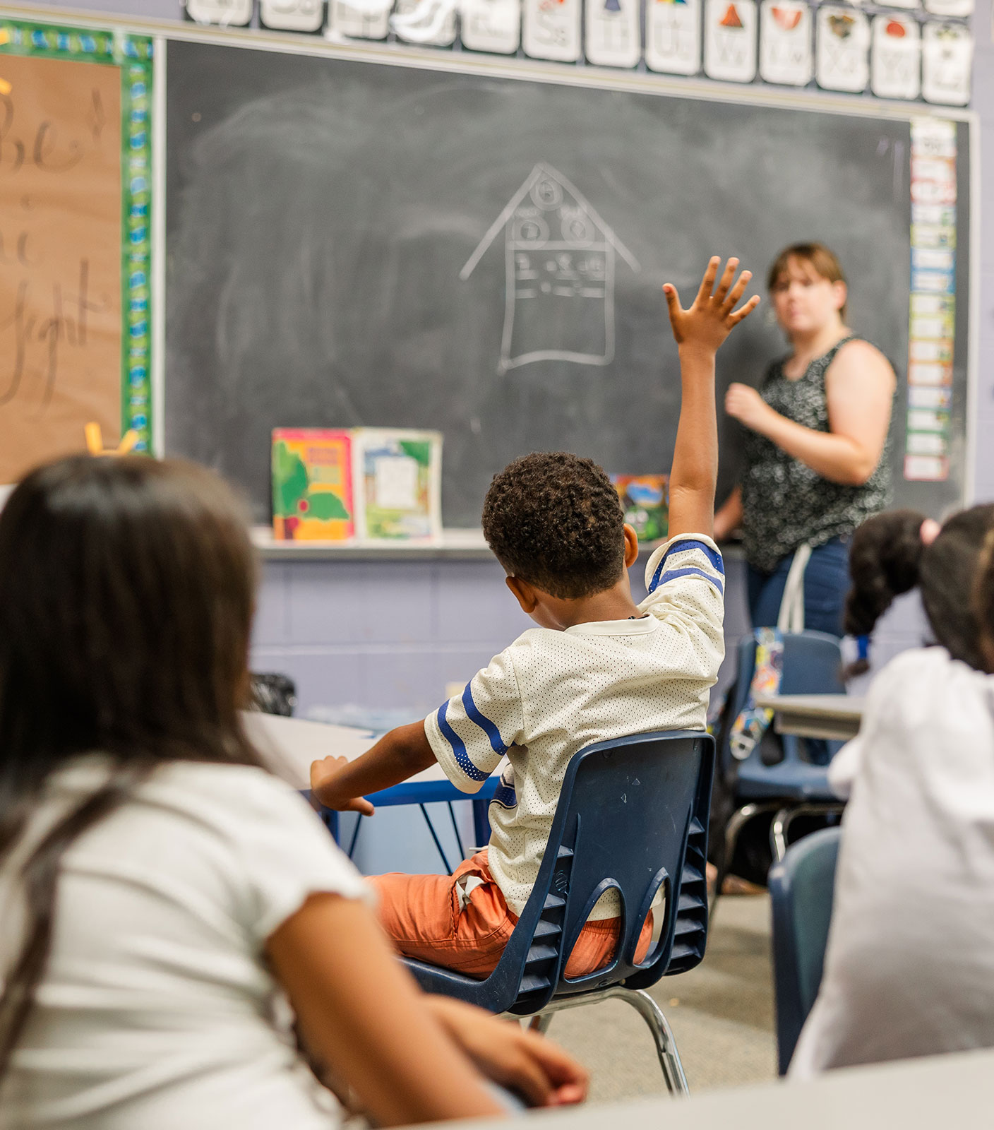 A student raising his hand in an Outreach-supported classroom